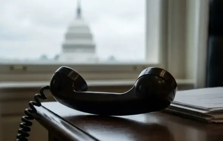 Vintage black telephone receiver on wooden desk with US Capitol building in background, representing financial advice and consulting services from Michael Ryan Money.